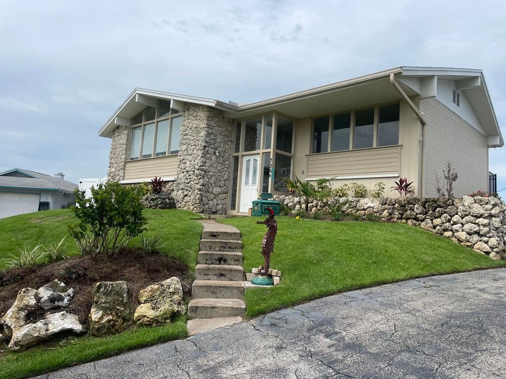 Modern single-story home with stone accents and lush landscaping on a curved driveway.