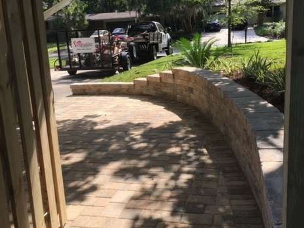 Curved stone retaining wall with a parked truck and trailer in the background.